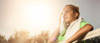 Child wiping sweat with towel hot humid sun tennis sports practice