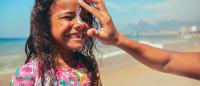 Little surfer swim girl in rashguard at beach sunscreen skin protection on face