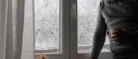 man looking sad by the window on a snowy day