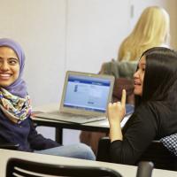 Two women of color in a classroom smiling