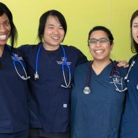 Four diverse nursing students standing together smiling.