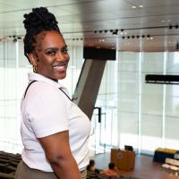A young woman smiles as she stands at the top of an auditorium